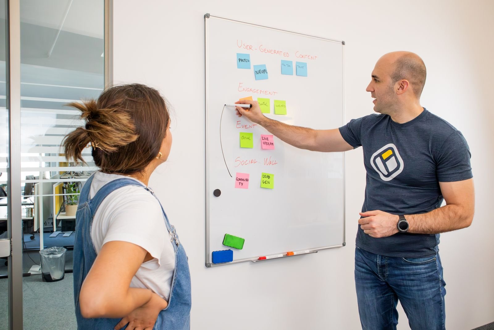 Two colleagues planning a campaign with sticky notes on a whiteboard